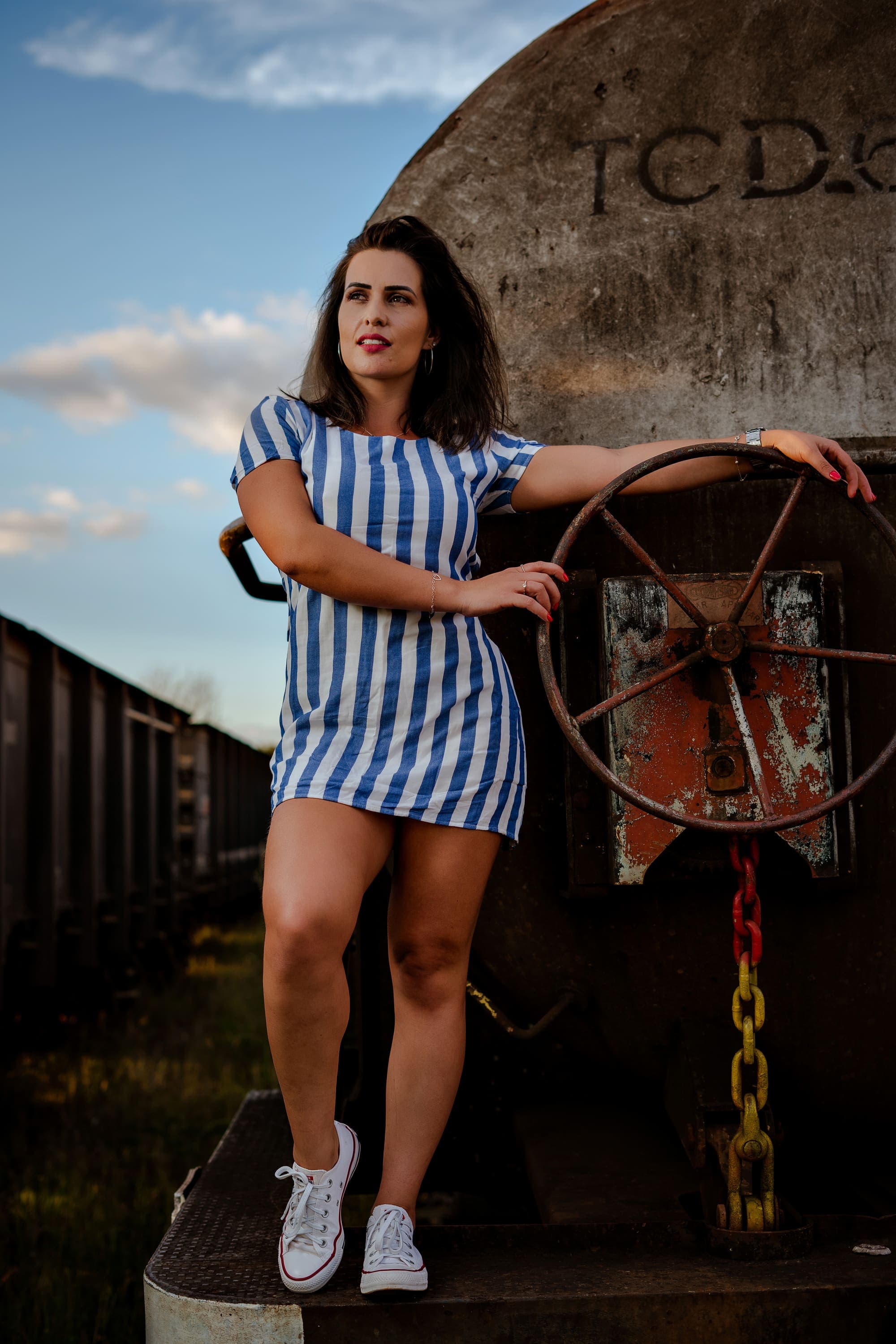 Retrato editorial ao ar livre em vagão de trem antigo, vestido listrado azul e branco, em Brasília